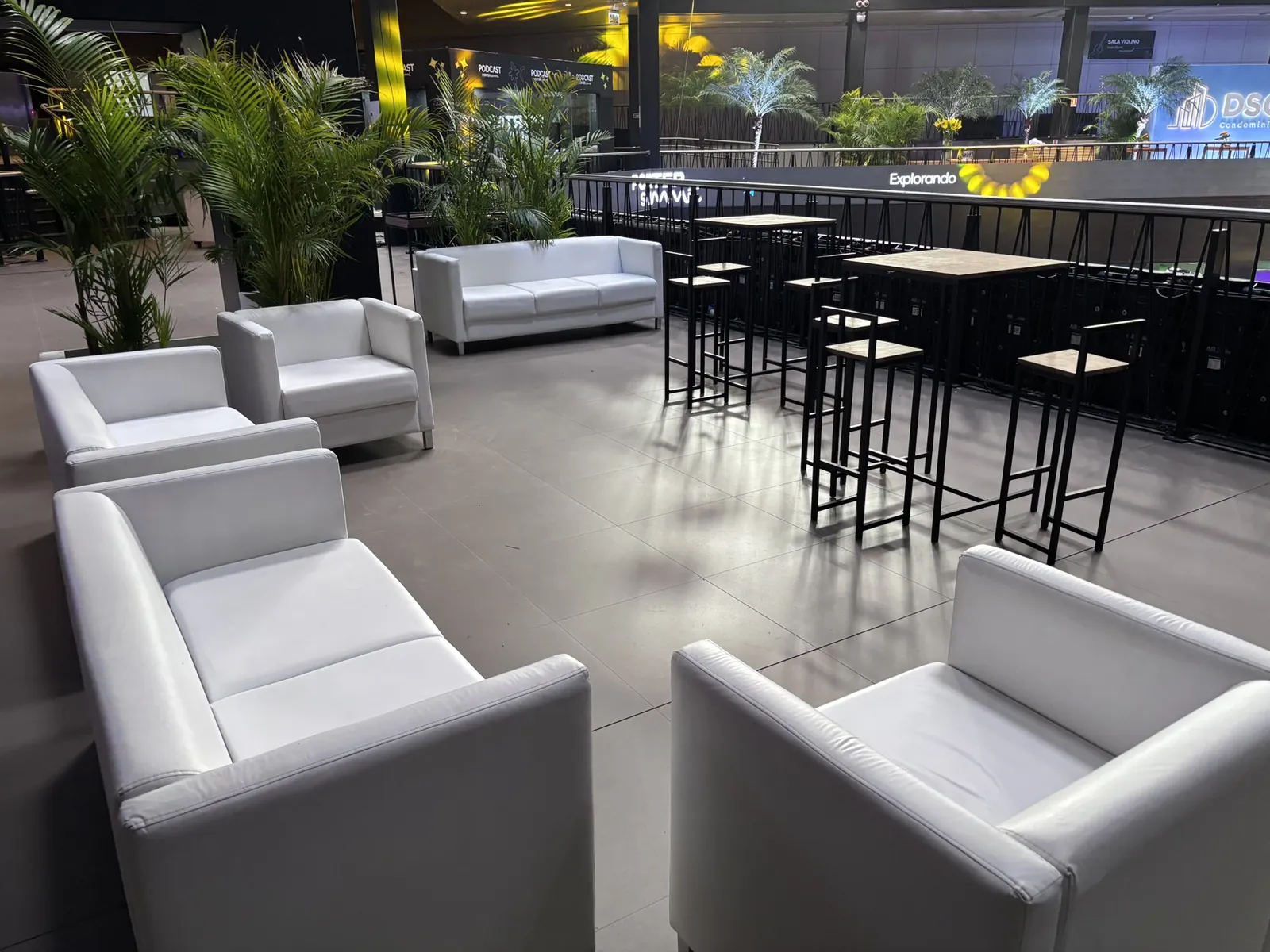 Lounge com sofás e mesas altas em evento