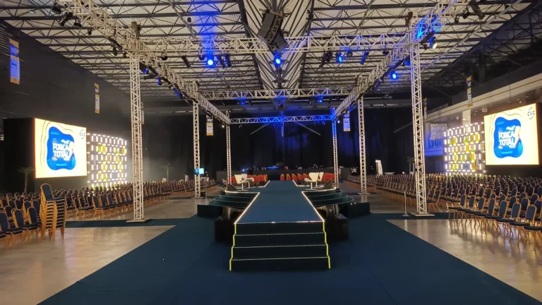 Palco com carpete azul e cadeiras em evento