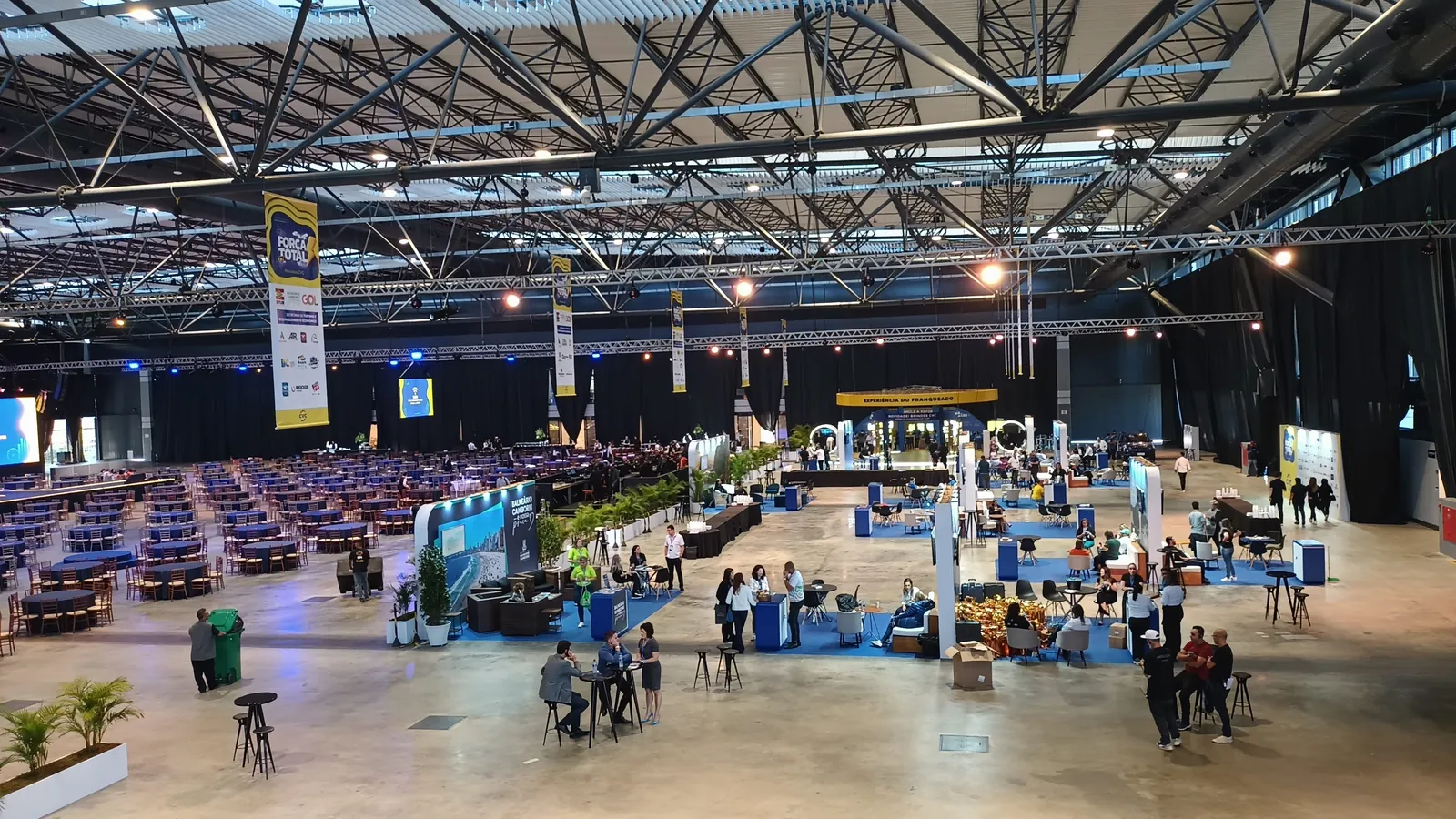 Pavilhão de feira com estandes e visitantes
