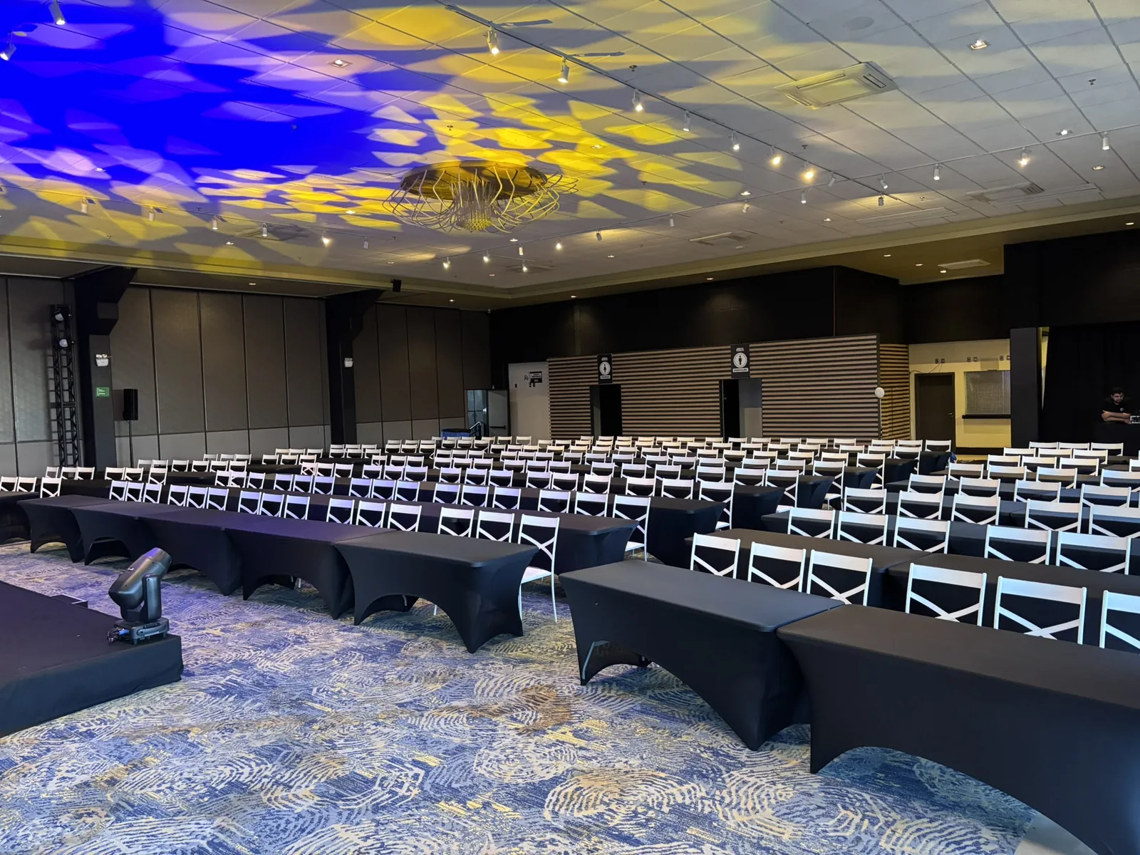 Salão de evento com forro iluminado e mesas