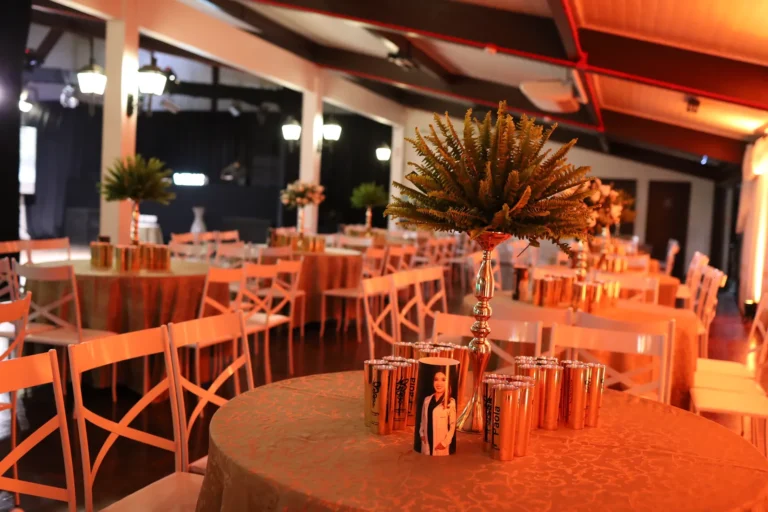 Mesas de jantar iluminadas com decoração verde no salão de formatura