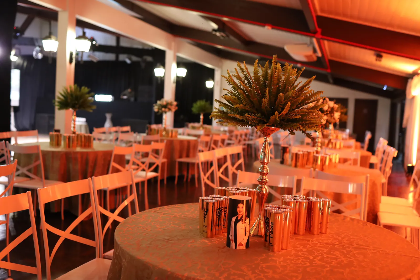 Mesas de jantar iluminadas com decoração verde no salão de formatura
